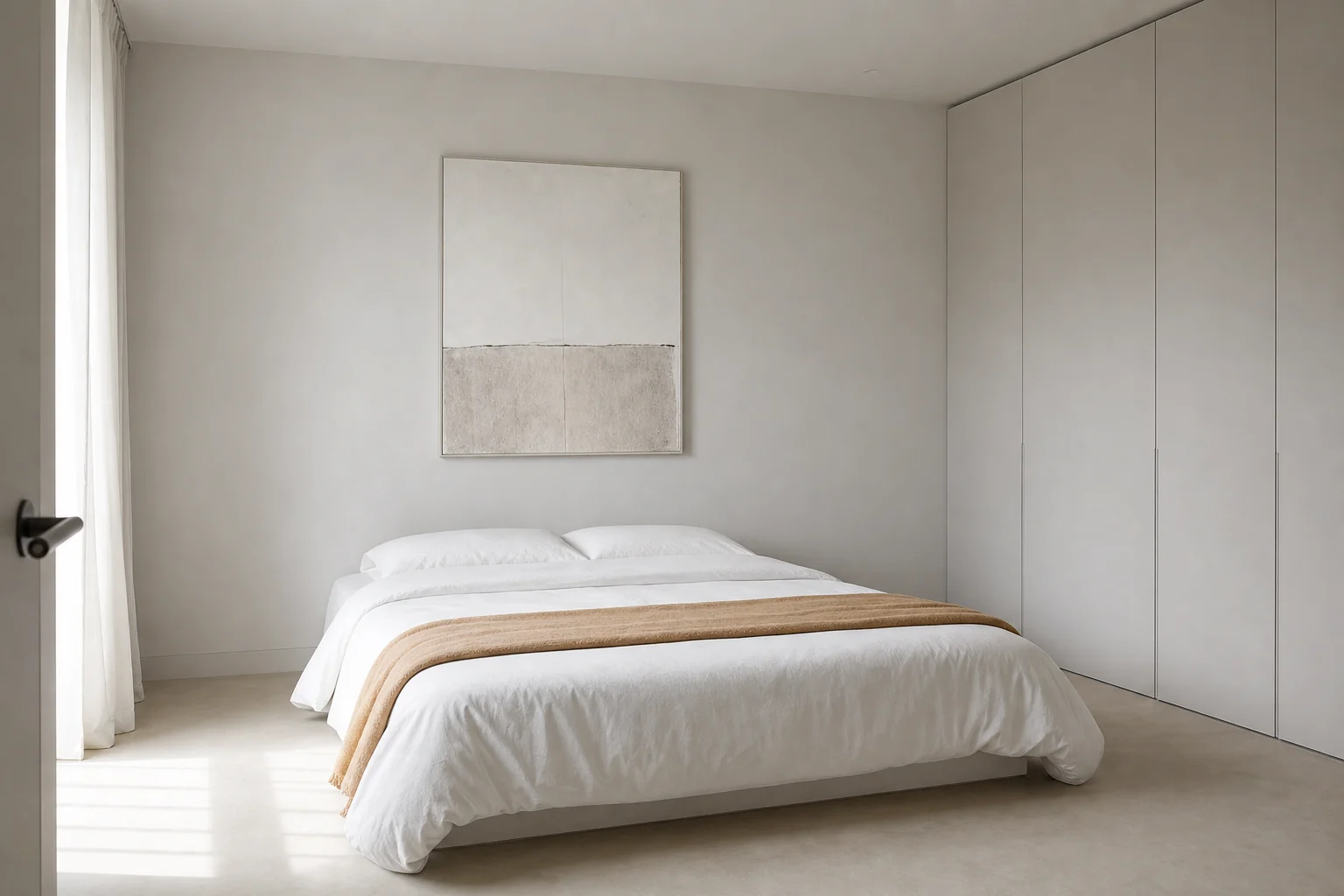 Minimalist bedroom with a headboard-free bed, plain white bedding, flush storage and one camel-colored throw